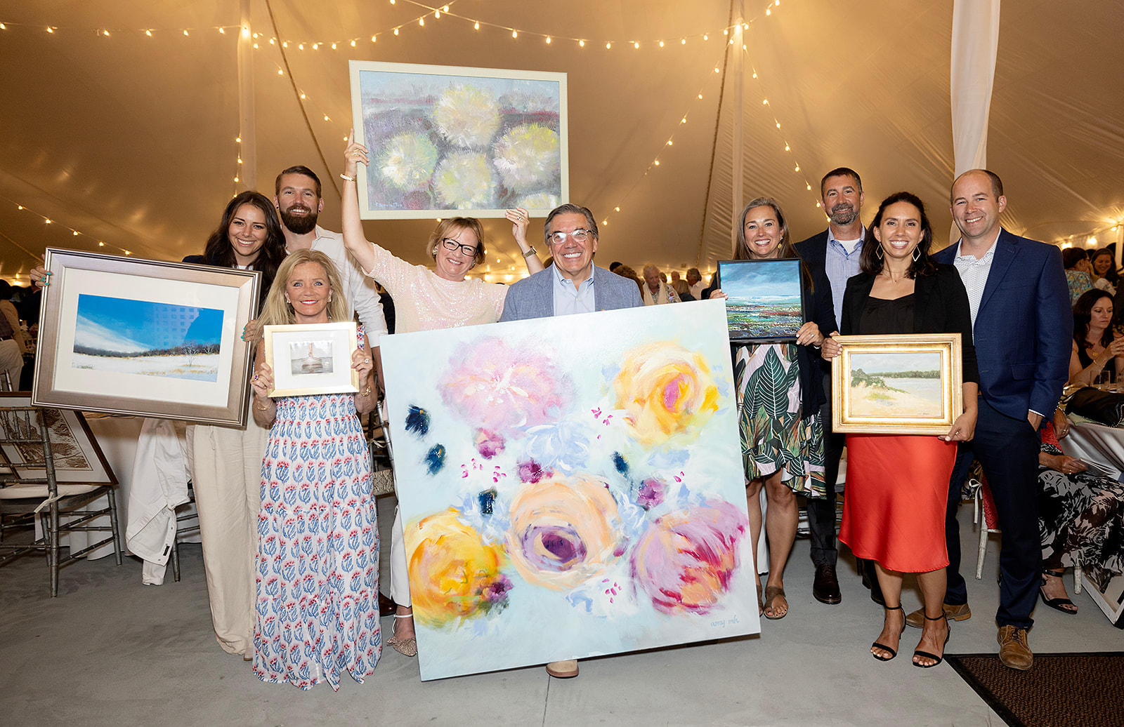 Guests holding their selected artwork after darting. Featuring Joan and Tom Sabatino, Gold Sponsors of this year’s Dart for Art (front left and front center).