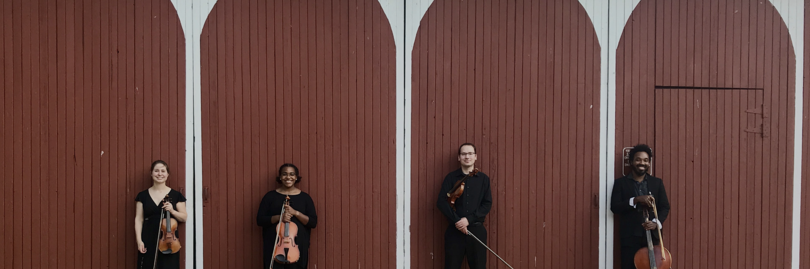 Quartet members in front of a barn