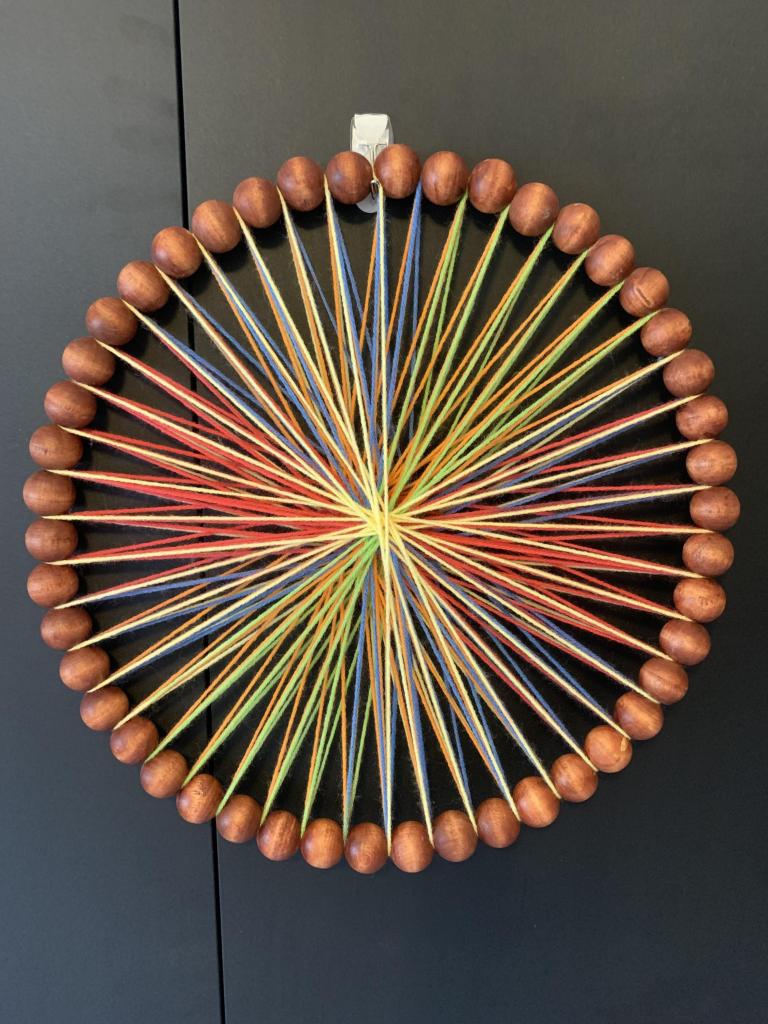 Wooden round circles with rainbow colored yarn wound throughout 16” x 16”